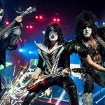 Kiss playing in 2013 during their Monster World Tour. From left to right: Gene Simmons, Eric Singer (in the background, on drums), Tommy Thayer and Paul Stanley.