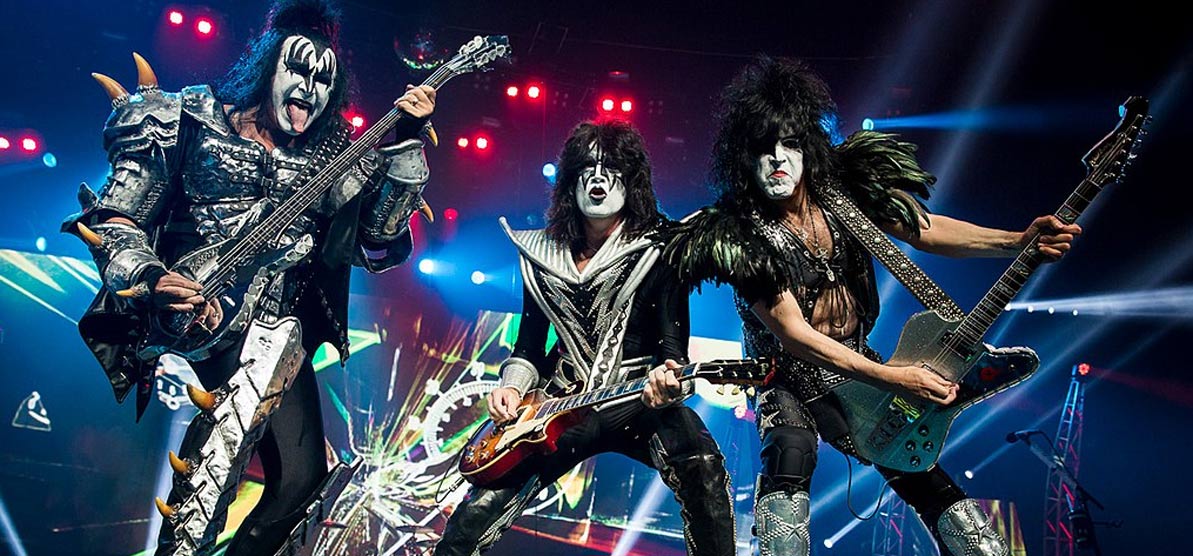 Kiss playing in 2013 during their Monster World Tour. From left to right: Gene Simmons, Eric Singer (in the background, on drums), Tommy Thayer and Paul Stanley.